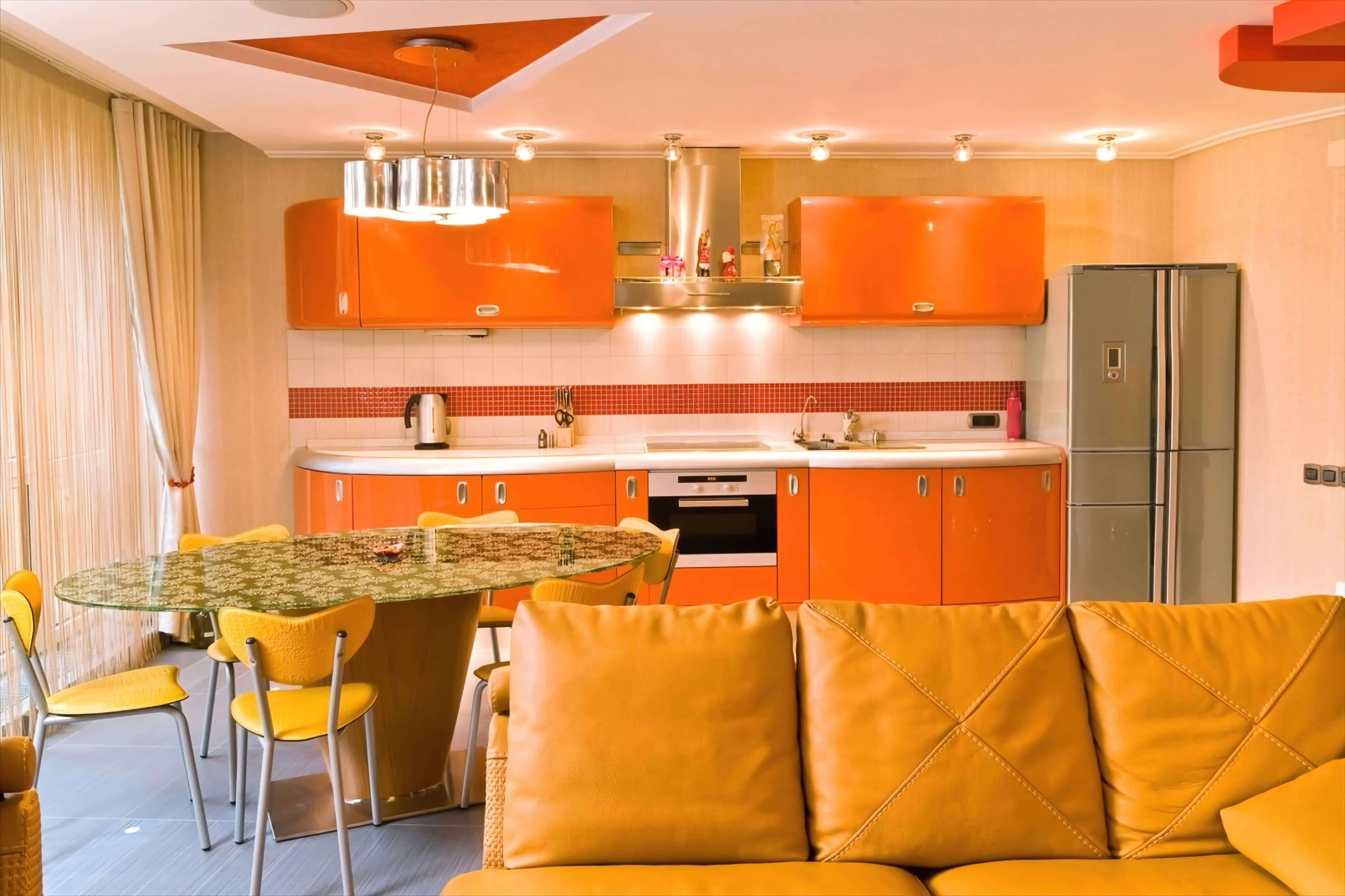 Кухня. Оранжевый кухонный гарнитур, диван, потолок