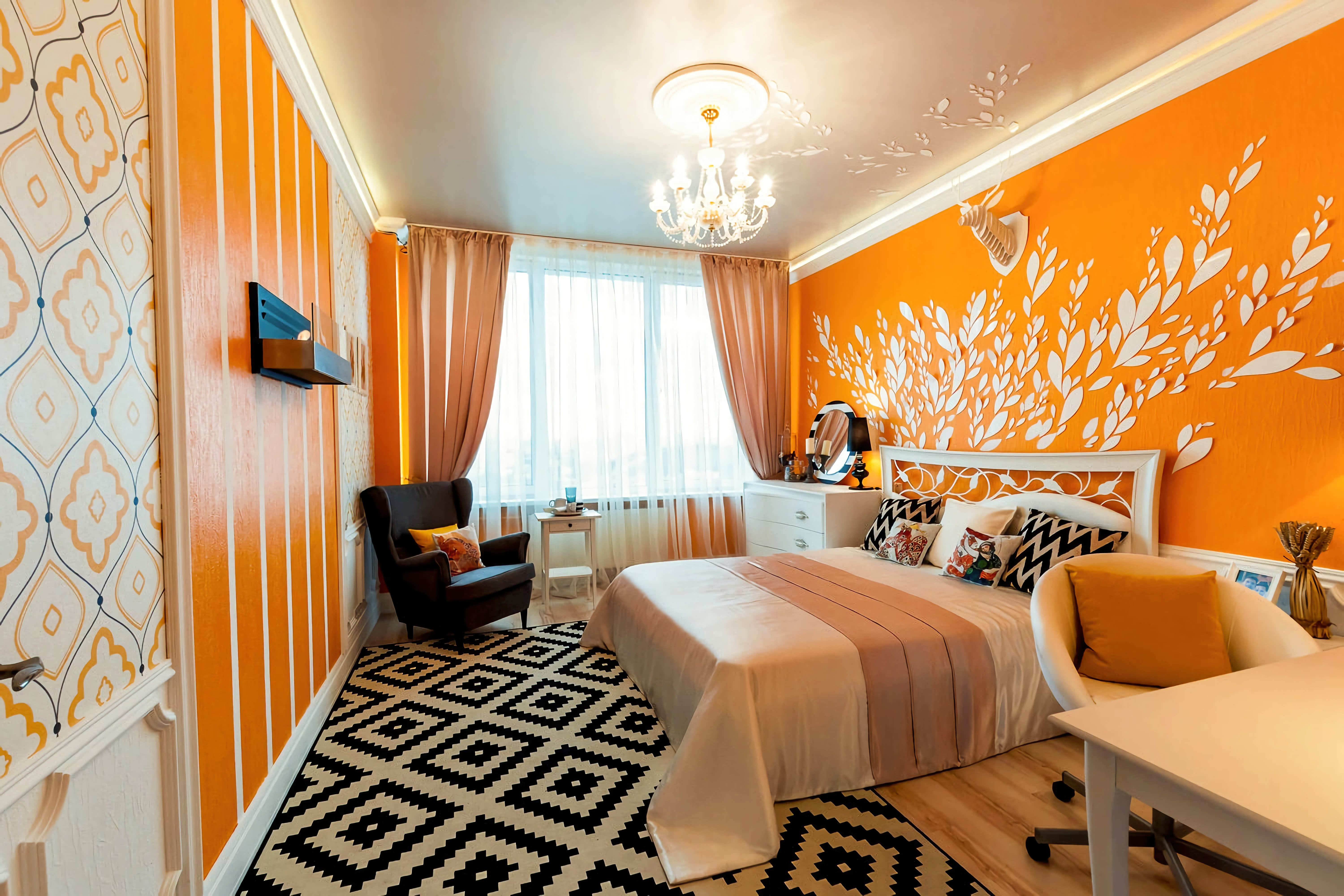 Спальня. Оранжевые стены, шторы. Черное кресло. Светлый потолок